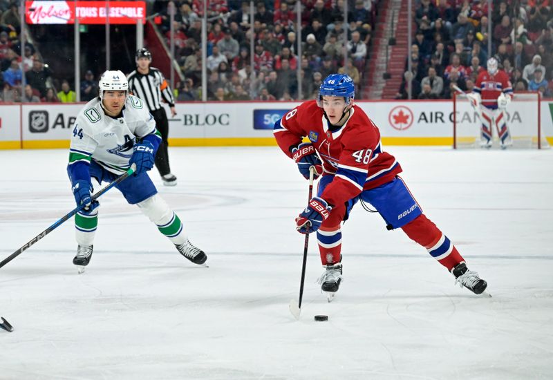 Jan 6, 2025; Montreal, Quebec, CAN; Montreal Canadiens defenseman Lane Hutson (48) plays the puck and Vancouver Canucks forward Kiefer Sherwood (44) defends during the second period at the Bell Centre. Mandatory Credit: Eric Bolte-Imagn Images