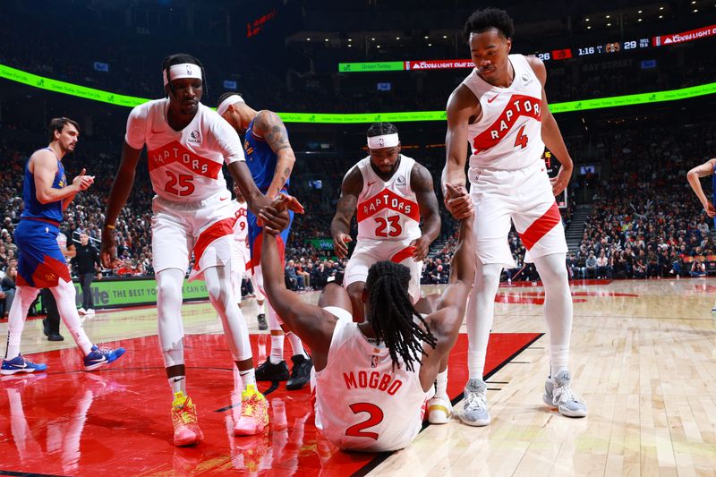 TORONTO, CANADA - OCTOBER 28: Chris Boucher #25 and Scottie Barnes #4 help up Jonathan Mogbo #2 of the Toronto Raptors during the game against the Denver Nuggets on October 28, 2024 at the Scotiabank Arena in Toronto, Ontario, Canada.  NOTE TO USER: User expressly acknowledges and agrees that, by downloading and or using this Photograph, user is consenting to the terms and conditions of the Getty Images License Agreement.  Mandatory Copyright Notice: Copyright 2024 NBAE (Photo by Vaughn Ridley/NBAE via Getty Images)