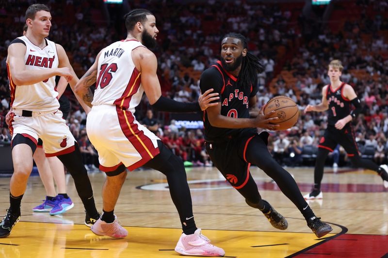 MIAMI, FLORIDA - APRIL 14: Javon Freeman-Liberty #0 of the Toronto Raptors drives against Caleb Martin #16 of the Miami Heat during the third quarter of the game at Kaseya Center on April 14, 2024 in Miami, Florida. NOTE TO USER: User expressly acknowledges and agrees that, by downloading and or using this photograph, User is consenting to the terms and conditions of the Getty Images License Agreement. (Photo by Megan Briggs/Getty Images)