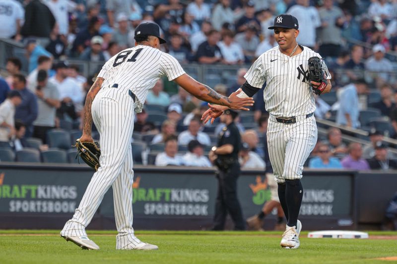 Aug 20, 2024; Bronx, New York, USA; New York Yankees starting pitcher Luis Gil (81) slaps hands with third baseman Oswald Peraza (91) during the first inning against the Cleveland Guardians at Yankee Stadium. Mandatory Credit: Vincent Carchietta-USA TODAY Sports