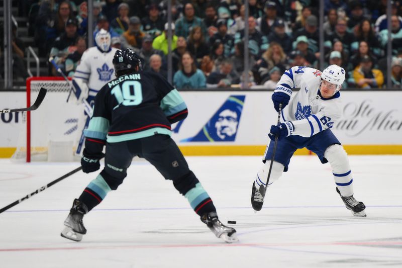 Jan 21, 2024; Seattle, Washington, USA; Toronto Maple Leafs center David Kampf (64) passes the puck past Seattle Kraken left wing Jared McCann (19) during the first period at Climate Pledge Arena. Mandatory Credit: Steven Bisig-USA TODAY Sports