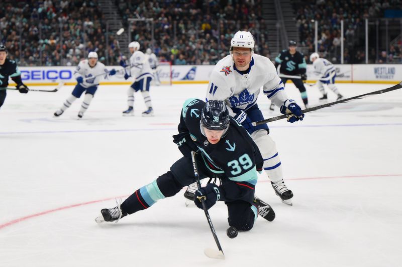 Jan 21, 2024; Seattle, Washington, USA; Seattle Kraken defenseman Ryker Evans (39) falls on the puck after being cross-checked by Toronto Maple Leafs center Max Domi (11) during the first period at Climate Pledge Arena. Mandatory Credit: Steven Bisig-USA TODAY Sports