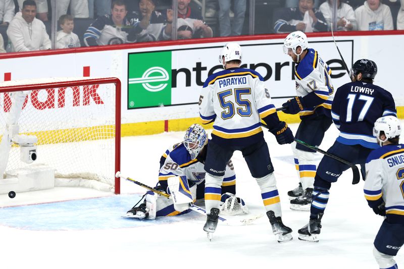 May 4, 2025; Winnipeg, Manitoba, CAN; Winnipeg Jets center Adam Lowry (17) scores a goal against St. Louis Blues goaltender Jordan Binnington (50) in the second overtime of game seven of the first round of the 2025 Stanley Cup Playoffs at Canada Life Centre. Mandatory Credit: James Carey Lauder-Imagn Images