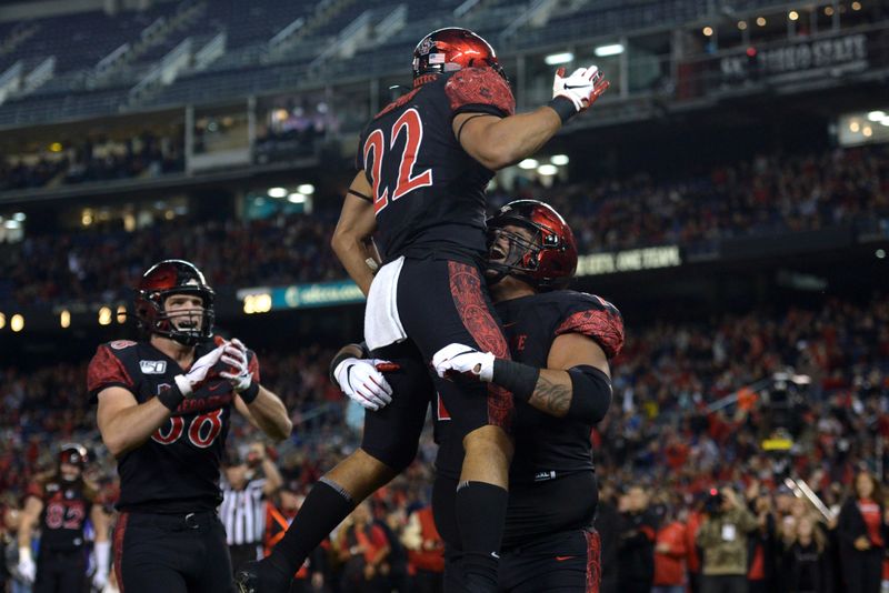 Nov 15, 2019; San Diego, CA, USA; San Diego State Aztecs running back Chase Jasmin (22) is hoisted by offensive lineman William Dunkle (73) during the first quarter after a touchdown against the Fresno State Bulldogs at SDCCU Stadium. Mandatory Credit: Jake Roth-USA TODAY Sports