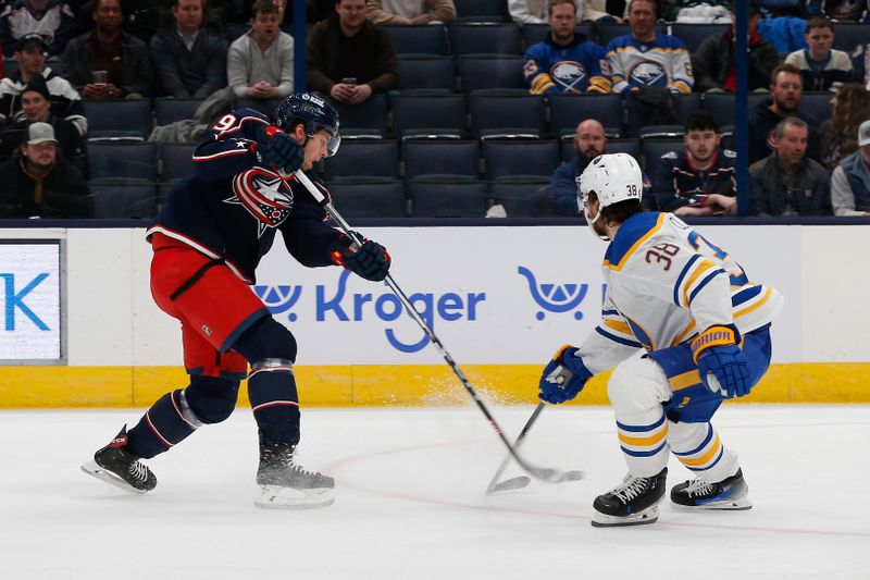 Feb 23, 2024; Columbus, Ohio, USA; Columbus Blue Jackets right wing Yegor Chinakhov (59) shoots over the stick of Buffalo Sabres defenseman Kale Clague (38) during the first period at Nationwide Arena. Mandatory Credit: Russell LaBounty-USA TODAY Sports