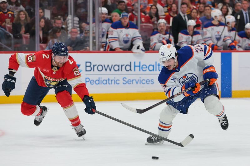 Nov 22, 2025; Sunrise, Florida, USA; Edmonton Oilers center Matt Savoie (22) moves the puck against Florida Panthers defenseman Jeff Petry (2) during the second period at Amerant Bank Arena. Mandatory Credit: Sam Navarro-Imagn Images