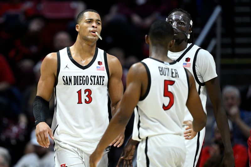 Dec 21, 2023; San Diego, California, USA; San Diego State Aztecs forward Jaedon LeDee (13) celebrates with guard Lamont Butler (5) and forward Jay Pal (right) during the second half against the Stanford Cardinal at Viejas Arena. Mandatory Credit: Orlando Ramirez-USA TODAY Sports