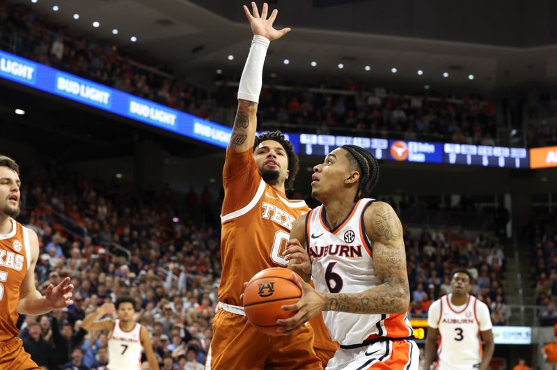 Jan 28, 2026; Auburn, Alabama, USA;  TTexas Longhorns guard Jordan Pope (0) grabs the arm and fouls Auburn Tigers guard Elyjah Freeman (6) during the second half at Neville Arena. Mandatory Credit: John Reed-Imagn Images