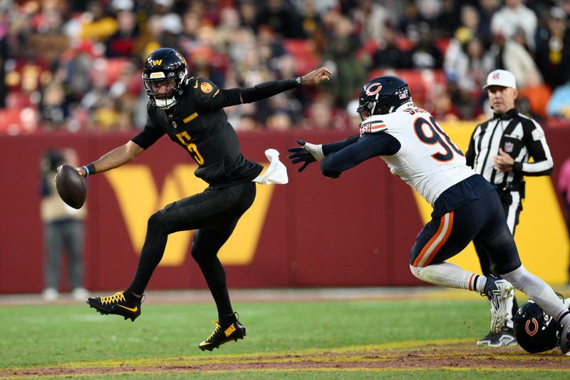 Washington Commanders quarterback Jayden Daniels (5) scrambles away from Chicago Bears defensive end Montez Sweat (98) in the second half of an NFL football game Sunday, Oct. 27, 2024, in Landover, Md. (AP Photo/Nick Wass)