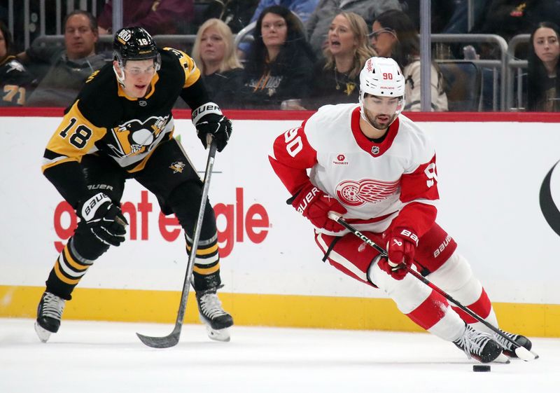 Nov 13, 2024; Pittsburgh, Pennsylvania, USA;  Detroit Red Wings center Joe Veleno (90) skates with the puck ahead of Pittsburgh Penguins right wing Jesse Puljujarvi (18) during the first period at PPG Paints Arena. Mandatory Credit: Charles LeClaire-Imagn Images