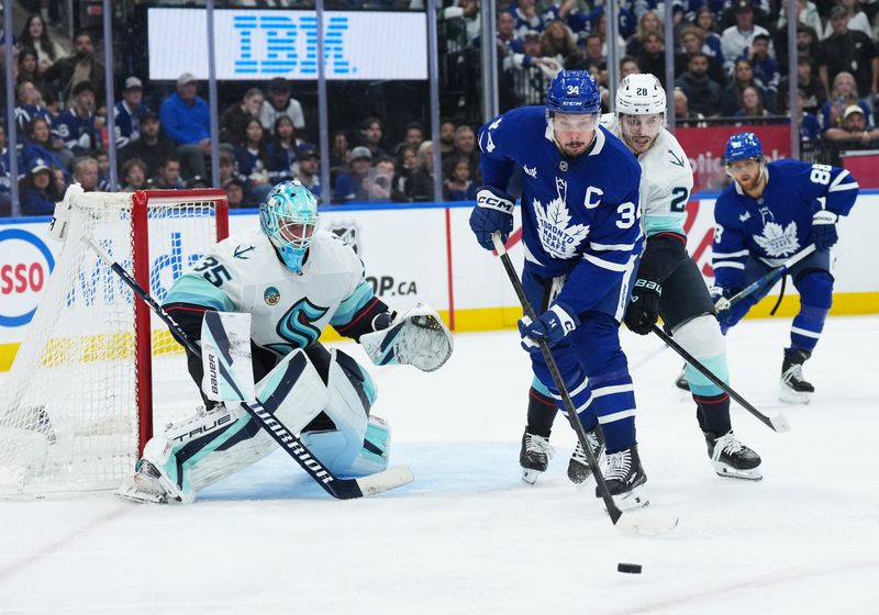 Oct 18, 2025; Toronto, Ontario, CAN; Toronto Maple Leafs center Auston Matthews (34) controls the puck defended by Seattle Kraken defenseman Joshua Mahura (28) during the third period at Scotiabank Arena. Mandatory Credit: Nick Turchiaro-Imagn Images
