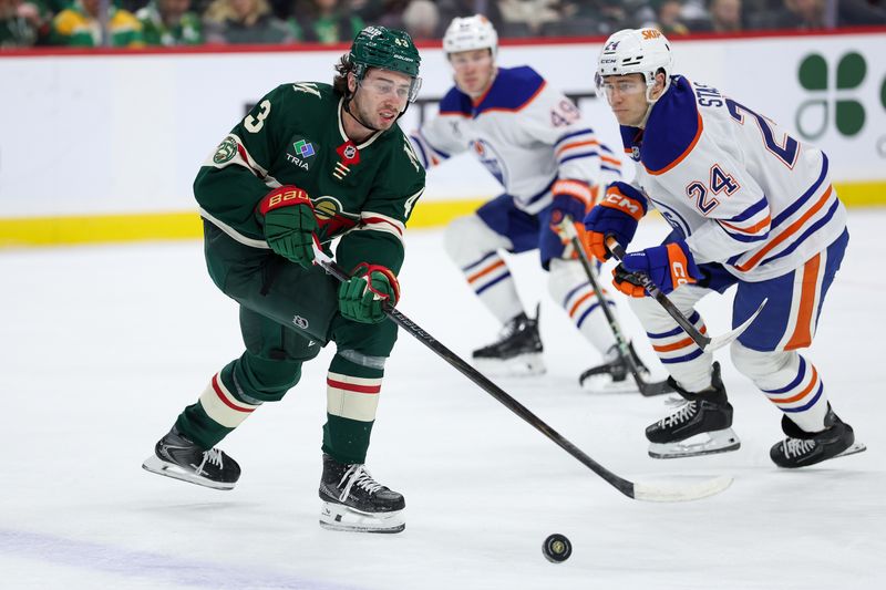 Dec 20, 2025; Saint Paul, Minnesota, USA; Minnesota Wild defenseman Quinn Hughes (43) reaches for the puck as Edmonton Oilers defenseman Spencer Stastney (24) defends during the first period at Grand Casino Arena. Mandatory Credit: Matt Krohn-Imagn Images