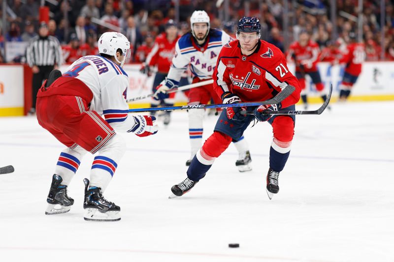 Oct 29, 2024; Washington, District of Columbia, USA; Washington Capitals center Aliaksei Protas (21) attempts to skate with the puck around New York Rangers defenseman Braden Schneider (4) in the third period at Capital One Arena. Mandatory Credit: Geoff Burke-Imagn Images