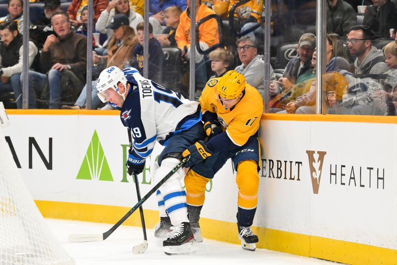 Nov 29, 2025; Nashville, Tennessee, USA;  Nashville Predators center Tyson Jost (17) vies for the puck behind the goal against Winnipeg Jets center Jonathan Toews (19) during the first period at Bridgestone Arena. Mandatory Credit: Steve Roberts-Imagn Images