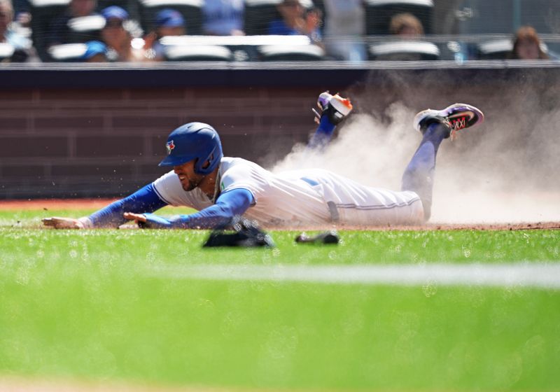 Jun 15, 2024; Toronto, Ontario, CAN; Toronto Blue Jays right fielder George Springer (4) slides into home plate scoring a run against the Cleveland Guardians during the fourth inning at Rogers Centre. Mandatory Credit: Nick Turchiaro-USA TODAY Sports