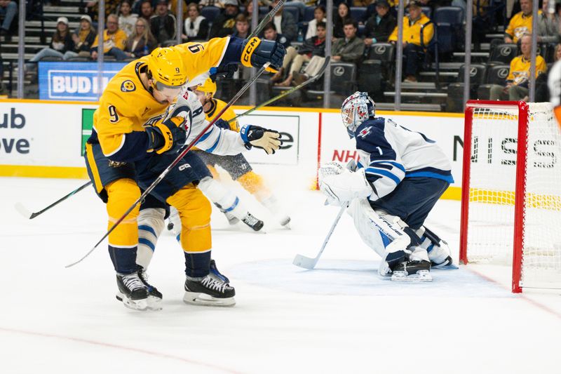 Nov 23, 2024; Nashville, Tennessee, USA;  Nashville Predators left wing Filip Forsberg (9) takes a puck to the helmet against the Winnipeg Jets during the first period at Bridgestone Arena. Mandatory Credit: Steve Roberts-Imagn Images