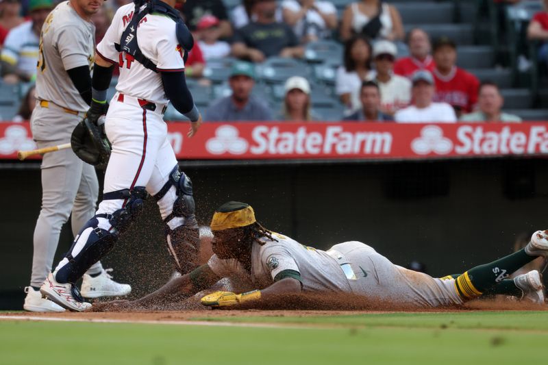 Jul 25, 2024; Anaheim, California, USA;  Oakland Athletics right fielder Lawrence Butler (4) slides safely into home to score a run during the first inning against the Los Angeles Angels at Angel Stadium. Mandatory Credit: Kiyoshi Mio-USA TODAY Sports