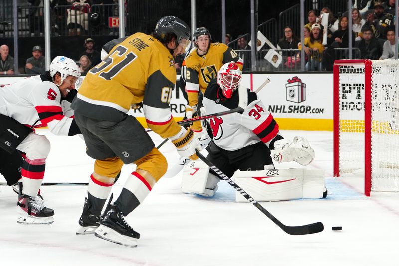 Dec 17, 2025; Las Vegas, Nevada, USA; New Jersey Devils goaltender Jake Allen (34) defends his net as Vegas Golden Knights right wing Mark Stone (61) pursues a loose puck during the second period at T-Mobile Arena. Mandatory Credit: Stephen R. Sylvanie-Imagn Images