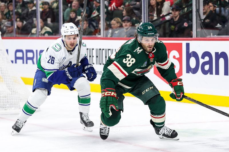 Dec 3, 2024; Saint Paul, Minnesota, USA; Minnesota Wild right wing Ryan Hartman (38) and Vancouver Canucks defenseman Erik Brannstrom (26) compete for the puck during the second period at Xcel Energy Center. Mandatory Credit: Matt Krohn-Imagn Images