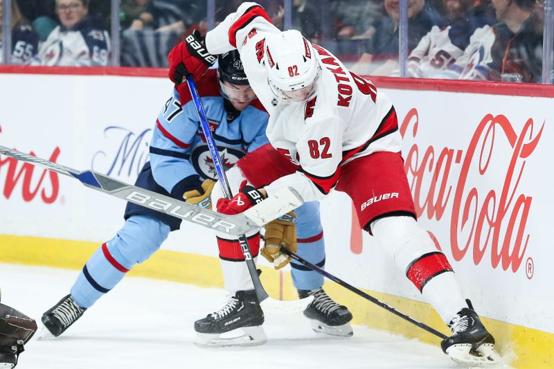 Dec 4, 2023; Winnipeg, Manitoba, CAN;   Winnipeg Jets defenseman Declan Chisholm (47) battles Carolina Hurricanes forward Jesperi Kotkaniemi (82) for the puck during the first period at Canada Life Centre. Mandatory Credit: Terrence Lee-USA TODAY Sports