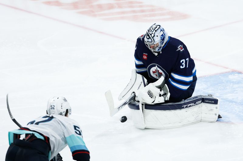 Apr 16, 2024; Winnipeg, Manitoba, CAN;  Winnipeg Jets goalie Connor Hellebuyck (37) makes a save as Seattle Kraken forward Tye Kartye (52) looks for a rebound during the third period at Canada Life Centre. Mandatory Credit: Terrence Lee-USA TODAY Sports