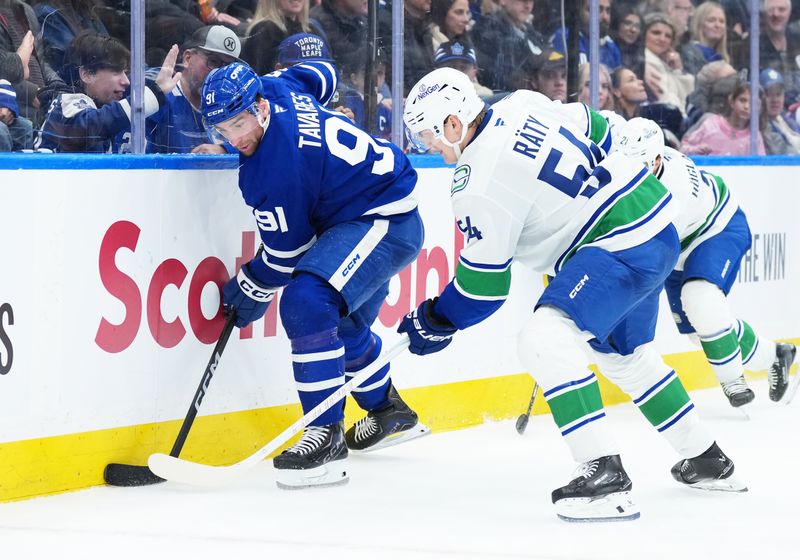 Jan 10, 2026; Toronto, Ontario, CAN;  Toronto Maple Leafs center John Tavares (91) battles for the puck along the boards with Vancouver Canucks center Aatu Raty (54) during the third period at Scotiabank Arena. Mandatory Credit: Nick Turchiaro-Imagn Images
