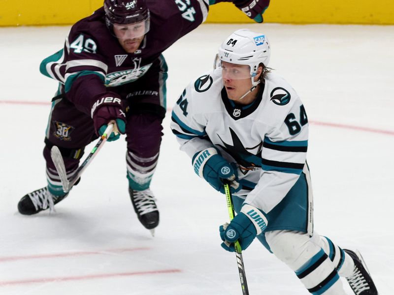 Nov 12, 2023; Anaheim, California, USA; San Jose Sharks right wing Mitchell Russell (64) keeps the puck from Anaheim Ducks left wing Max Jones (49) during the third period at Honda Center. Mandatory Credit: Jason Parkhurst-USA TODAY Sports