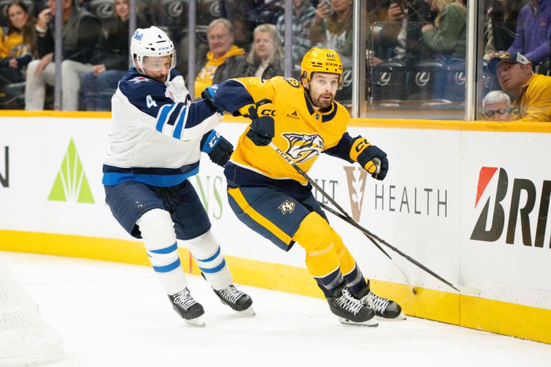 Nov 23, 2024; Nashville, Tennessee, USA;  Nashville Predators center Tommy Novak (82) and Winnipeg Jets defenseman Neal Pionk (4) fight for the puck during the first period at Bridgestone Arena. Mandatory Credit: Steve Roberts-Imagn Images