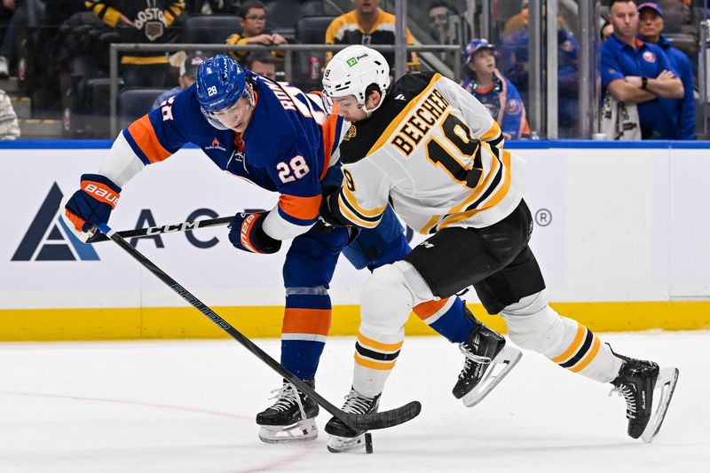 Nov 27, 2024; Elmont, New York, USA;  New York Islanders defenseman Alexander Romanov (28) defends against Boston Bruins center John Beecher (19) during the first period at UBS Arena. Mandatory Credit: Dennis Schneidler-Imagn Images