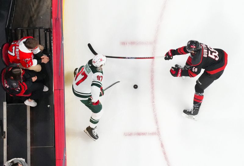 Jan 21, 2024; Raleigh, North Carolina, USA;  Minnesota Wild left wing Kirill Kaprizov (97) skates with the puck against Carolina Hurricanes left wing Michael Bunting (58) during the second period at PNC Arena. Mandatory Credit: James Guillory-USA TODAY Sports