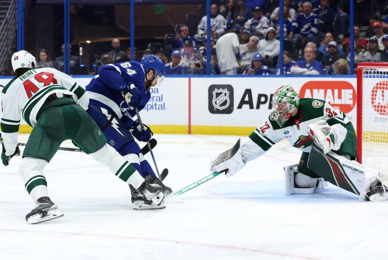 Jan 18, 2024; Tampa, Florida, USA; Tampa Bay Lightning center Tyler Motte (64) shoots as Minnesota Wild defenseman Daemon Hunt (48) and goaltender Filip Gustavsson (32) defend during the third period at Amalie Arena. Mandatory Credit: Kim Klement Neitzel-USA TODAY Sports