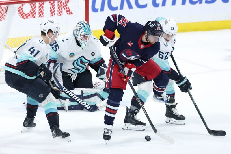 Jan 16, 2025; Winnipeg, Manitoba, CAN; Winnipeg Jets left wing Kyle Connor (81) and Seattle Kraken defenseman Brandon Montour (62) eye and incoming shot on Seattle Kraken goaltender Joey Daccord (35) in the third period at Canada Life Centre. Mandatory Credit: James Carey Lauder-Imagn Images