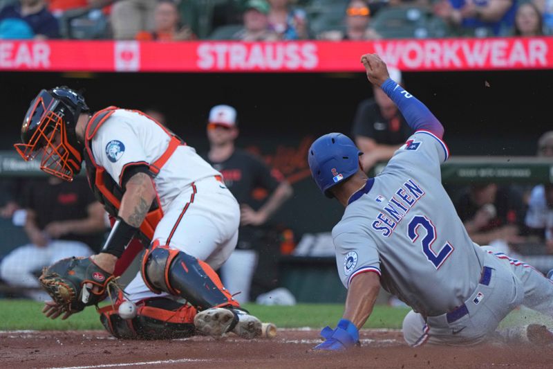 Jun 24, 2025; Baltimore, Maryland, USA; Texas Rangers second baseman Marcus Semien (2) slides safely to score during the third inning past Baltimore Orioles catcher Gary Sanchez (99) at Oriole Park at Camden Yards. Mandatory Credit: Mitch Stringer-Imagn Images