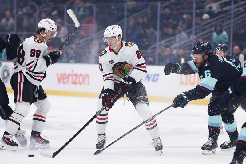 Nov 3, 2025; Seattle, Washington, USA; Chicago Blackhawks center Ryan Greene (20) and Seattle Kraken defenseman Adam Larsson (6) battle for the puck in the first period at Climate Pledge Arena. Mandatory Credit: Kevin Ng-Imagn Images