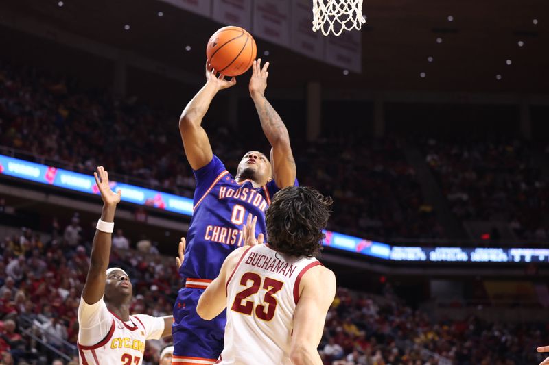 Dec 29, 2025; Ames, Iowa, USA; Houston Christian Huskies guard Demari Williams (0) shoots and scores over Iowa State Cyclones forward Blake Buchanan (23) during the second half at James H. Hilton Coliseum. Mandatory Credit: Reese Strickland-Imagn Images