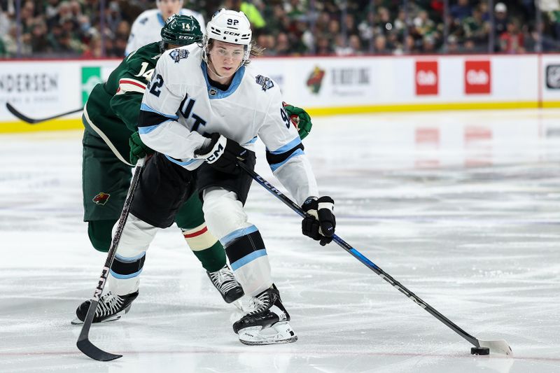 Jan 23, 2025; Saint Paul, Minnesota, USA; Utah Hockey Club center Logan Cooley (92) skates with the puck as Minnesota Wild center Joel Eriksson Ek (14) defends during the third period at Xcel Energy Center. Mandatory Credit: Matt Krohn-Imagn Images