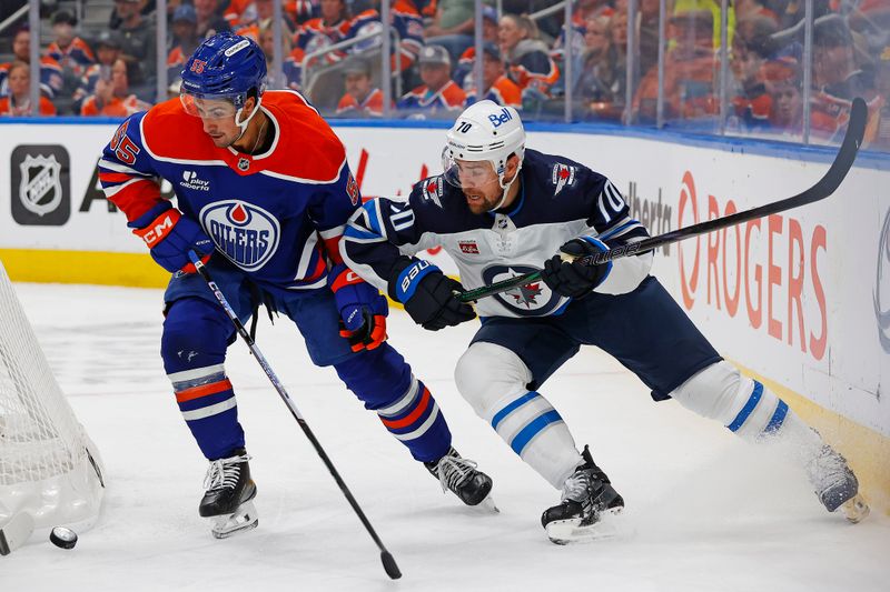 Sep 26, 2025; Edmonton, Alberta, CAN; Edmonton Oilers defensemen Cam Dineen (55) and Winnipeg Jets forward Tanner Pearson (70) battle for a loose puck during the second period at Rogers Place. Mandatory Credit: Perry Nelson-Imagn Images