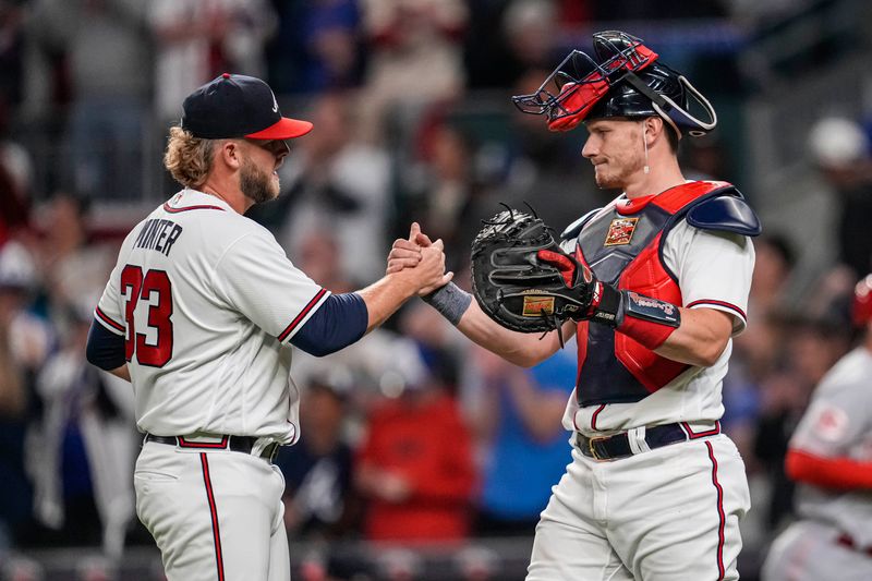 Apr 12, 2023; Cumberland, Georgia, USA; Atlanta Braves relief pitcher A.J. Minter (33) and catcher Sean Murphy (12) react after defeating the Cincinnati Reds at Truist Park. Mandatory Credit: Dale Zanine-USA TODAY Sports