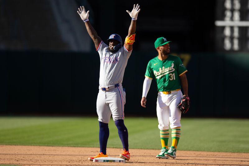 May 8, 2024; Oakland, California, USA; Texas Rangers designated hitter Adolis García (left) celebrates his RBI double as Oakland Athletics second baseman Abraham Toro (31) looks on during the eighth inning at Oakland-Alameda County Coliseum. Mandatory Credit: D. Ross Cameron-USA TODAY Sports