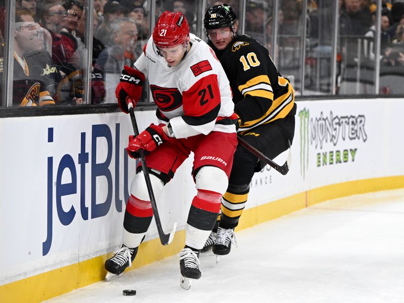 Nov 17, 2025; Boston, Massachusetts, USA; Carolina Hurricanes defenseman Alexander Nikishin (21) controls the puck against Boston Bruins left wing Riley Tufte (10) during the first period at the TD Garden. Mandatory Credit: Brian Fluharty-Imagn Images