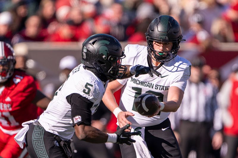 Nov 18, 2023; Bloomington, Indiana, USA; Michigan State Spartans quarterback Katin Houser (12) hands there ball off to Michigan State Spartans running back Nathan Carter (5) during the second quarter at Memorial Stadium. Mandatory Credit: Marc Lebryk-USA TODAY Sports