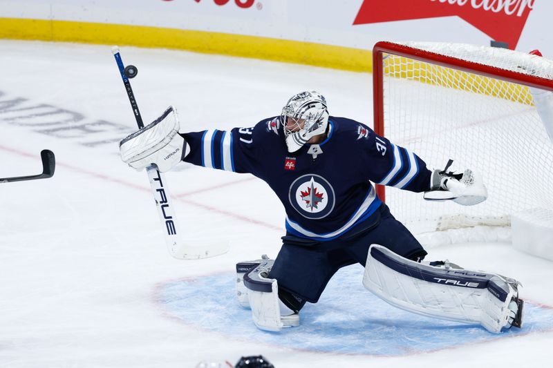 Oct 13, 2024; Winnipeg, Manitoba, CAN;  Winnipeg Jets goalie Connor Hellebuyck (37) deflects a Minnesota Wild shot during the third period at Canada Life Centre. Mandatory Credit: Terrence Lee-Imagn Images