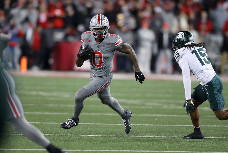 Nov 11, 2023; Columbus, Ohio, USA; Ohio State Buckeyes wide receiver Xavier Johnson (0) runs the ball as Michigan State Spartans defensive back Angelo Grose (15) defends during the first quarter at Ohio Stadium. Mandatory Credit: Joseph Maiorana-USA TODAY Sports