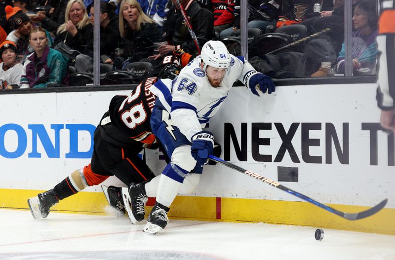 Mar 24, 2024; Anaheim, California, USA; Tampa Bay Lightning center Tyler Motte (64) takes the puck from Anaheim Ducks defenseman Gustav Lindstrom (28) during the first period at Honda Center. Mandatory Credit: Jason Parkhurst-USA TODAY Sports