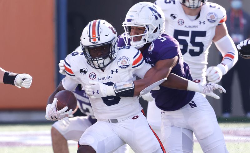 Jan 1, 2021; Orlando, FL, USA; Northwestern Wildcats defensive back JR Pace (5) tackles Auburn Tigers running back Shaun Shivers (8) during the second half at Camping World Stadium. Mandatory Credit: Reinhold Matay-USA TODAY Sports