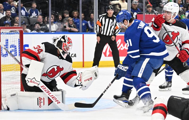 Apr 11, 2024; Toronto, Ontario, CAN; New Jersey Devils goalie Jake Allen (34) makes a glove save as Toronto Maple Leafs forward John Tavares (91) looks for a rebound in the first period at Scotiabank Arena. Mandatory Credit: Dan Hamilton-USA TODAY Sports