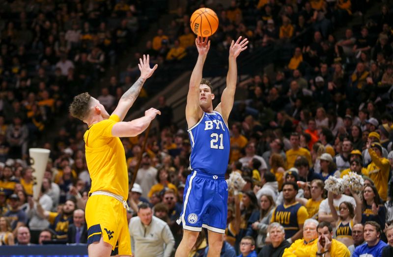 Feb 3, 2024; Morgantown, West Virginia, USA; Brigham Young Cougars guard Trevin Knell (21) shoots a three pointer over West Virginia Mountaineers forward Quinn Slazinski (11) during the first half at WVU Coliseum. Mandatory Credit: Ben Queen-USA TODAY Sports