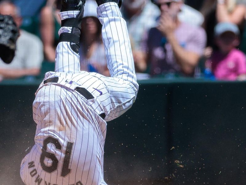 Jun 5, 2024; Denver, Colorado, USA; Colorado Rockies outfielder Charlie Blackmon (19) dives safely into first during the fourth inning against the Cincinnati Reds at Coors Field. Mandatory Credit: Andrew Wevers-USA TODAY Sports