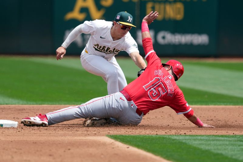 Jul 21, 2024; Oakland, California, USA; Los Angeles Angels second baseman Luis Guillorme (15) is tagged out by Oakland Athletics second baseman Zack Gelof (top) during the third inning at Oakland-Alameda County Coliseum. The call was originally safe and overturned after a video review. Mandatory Credit: Darren Yamashita-USA TODAY Sports