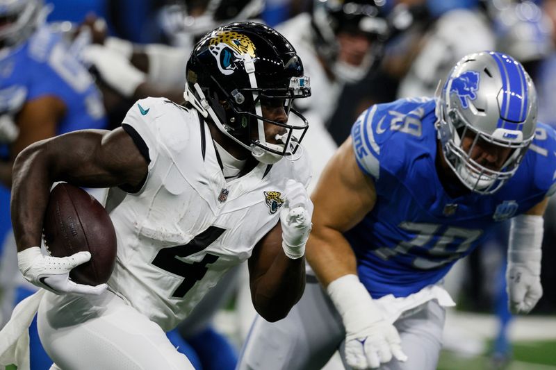 Jacksonville Jaguars running back Tank Bigsby (4) runs as Detroit Lions defensive end John Cominsky (79) defends during the first half of a preseason NFL football game, Saturday, Aug. 19, 2023, in Detroit. (AP Photo/Duane Burleson)